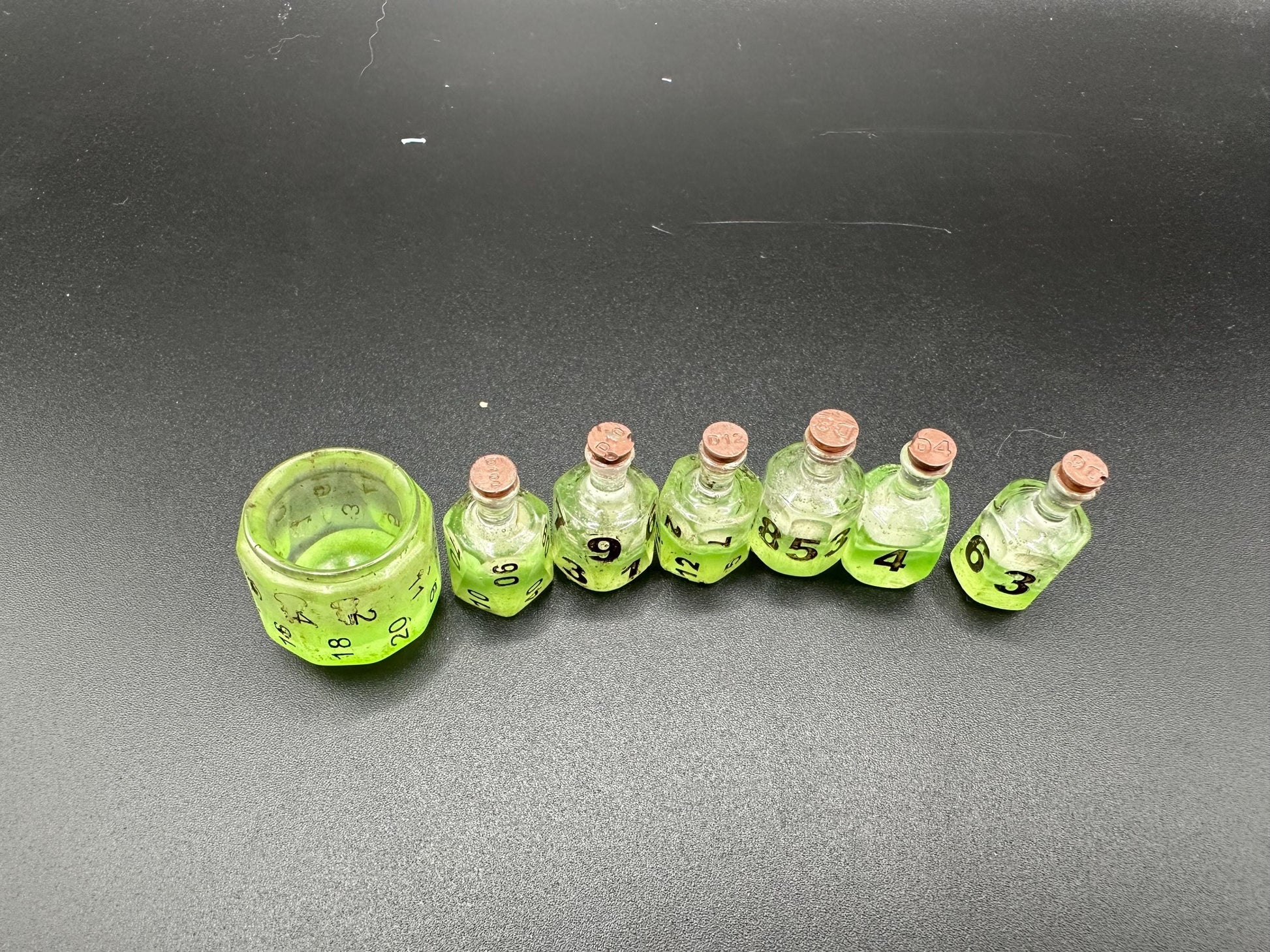 Green UV reactive dice set glowing like a witch’s potion; perfect for DnD, tabletop RPGs, and magical dice collectors; polyhedral set in moody lighting.