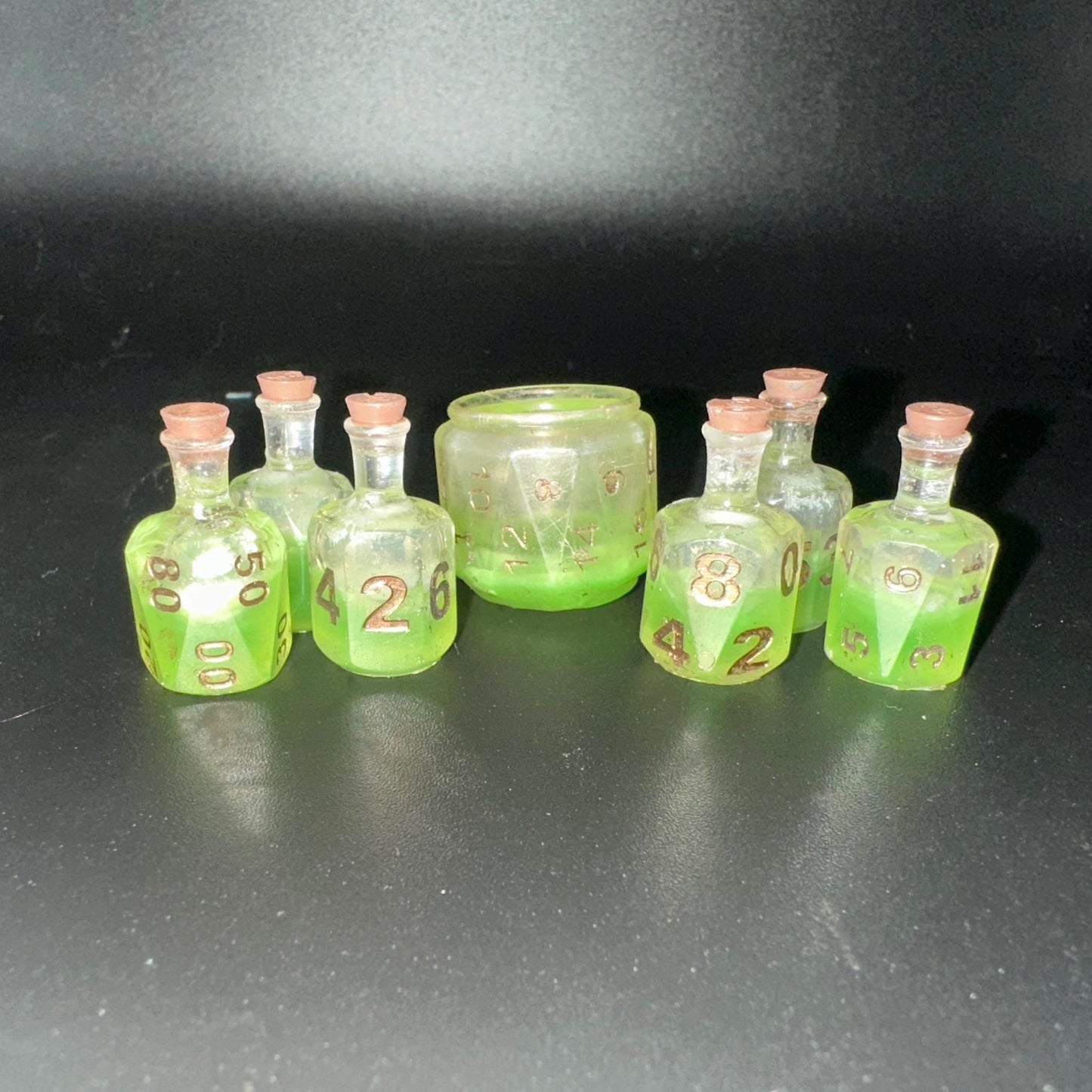 Green UV reactive dice set glowing like a witch’s potion; perfect for DnD, tabletop RPGs, and magical dice collectors; polyhedral set in moody lighting.