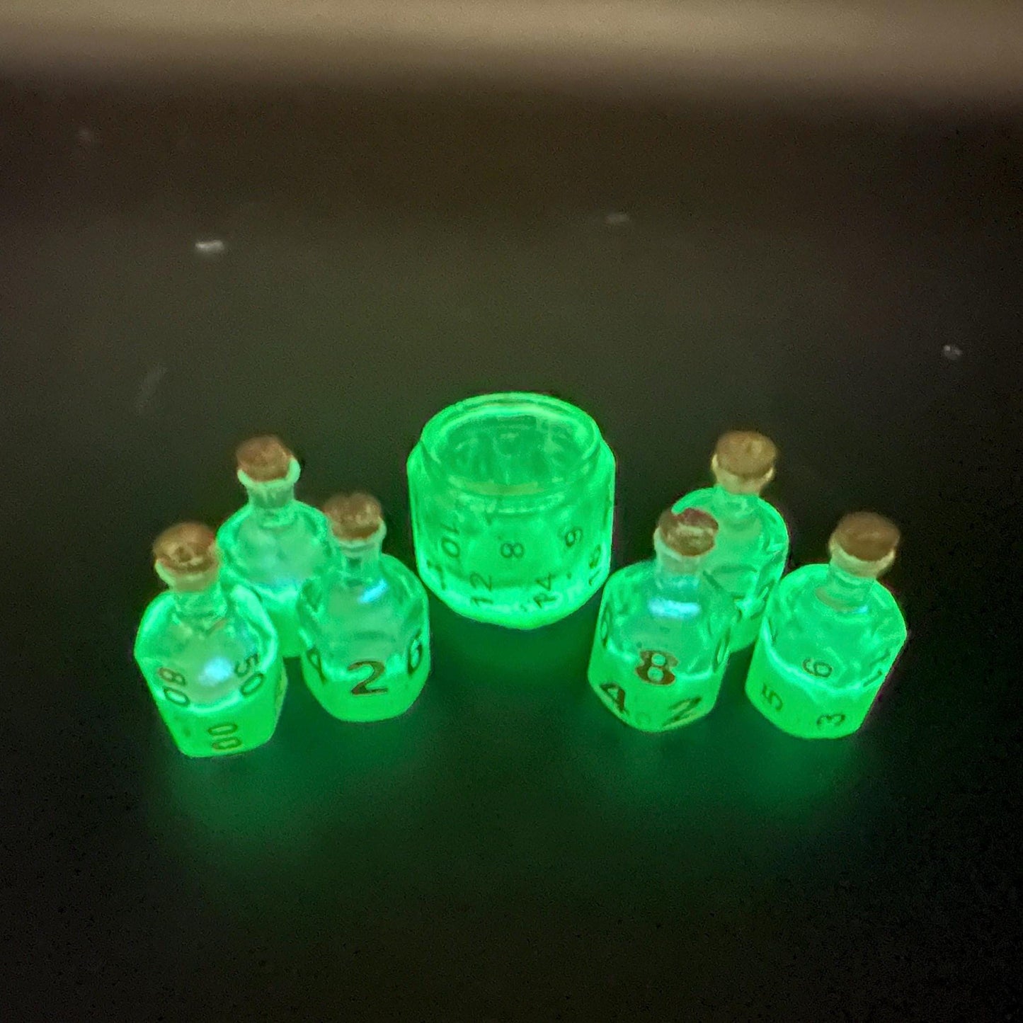 Green UV reactive dice set glowing like a witch’s potion; perfect for DnD, tabletop RPGs, and magical dice collectors; polyhedral set in moody lighting.