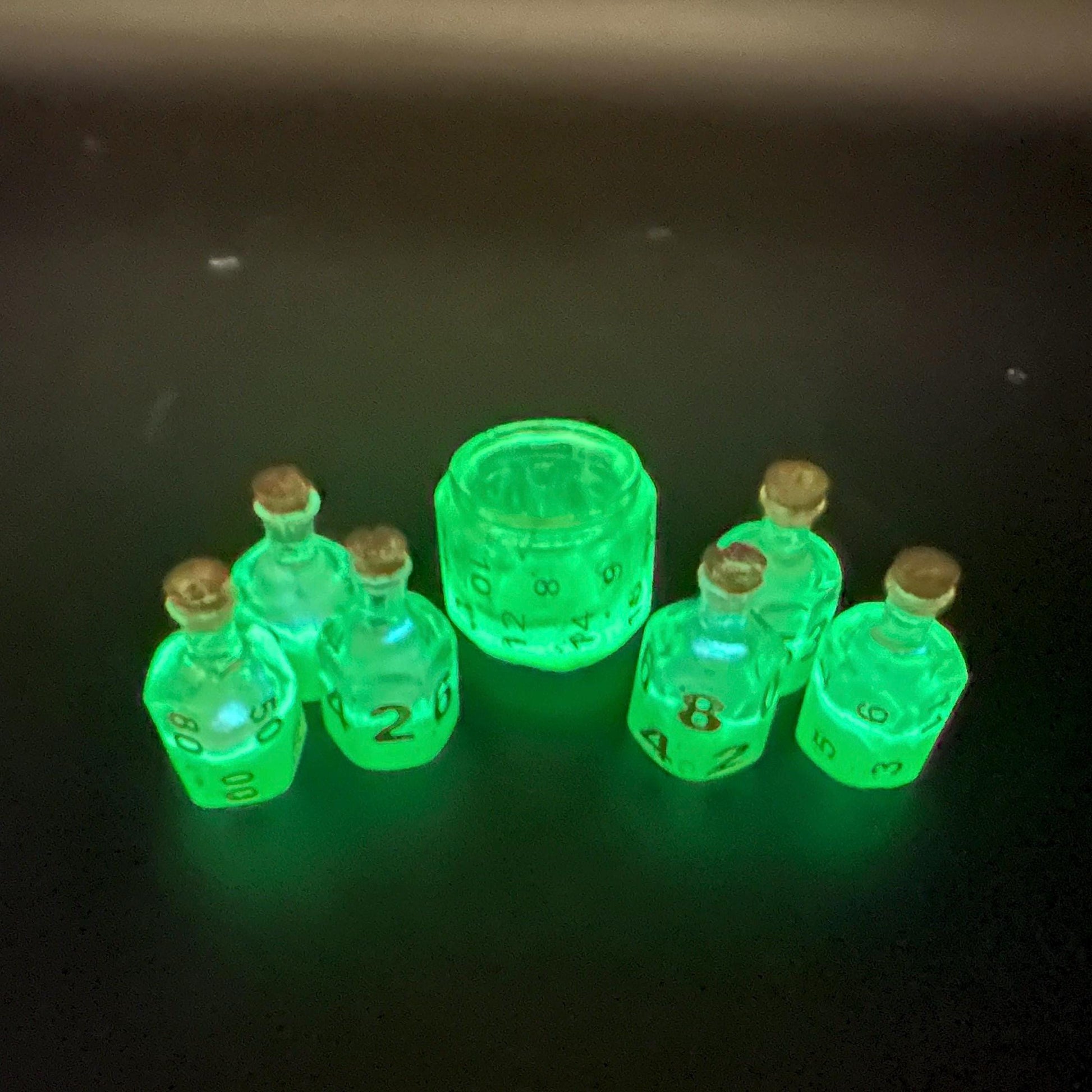 Green UV reactive dice set glowing like a witch’s potion; perfect for DnD, tabletop RPGs, and magical dice collectors; polyhedral set in moody lighting.