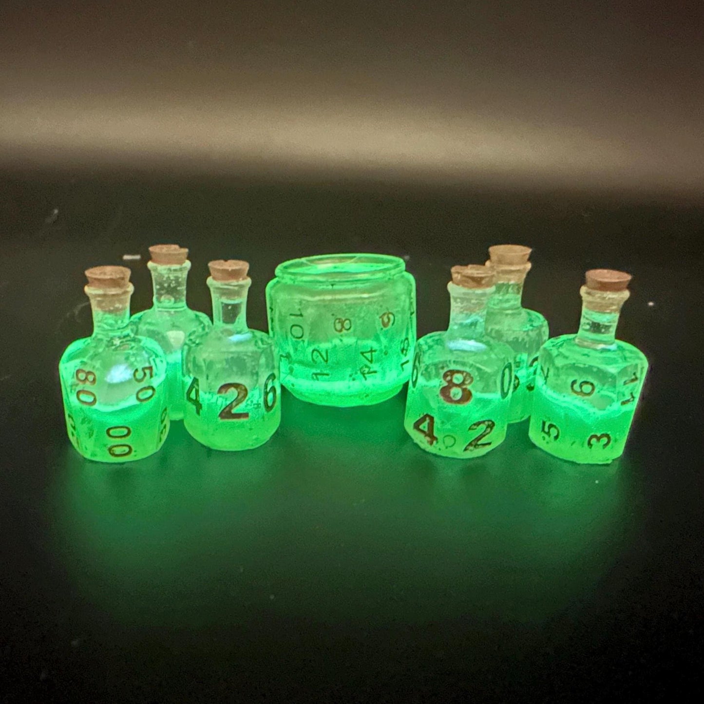 Green UV reactive dice set glowing like a witch’s potion; perfect for DnD, tabletop RPGs, and magical dice collectors; polyhedral set in moody lighting.