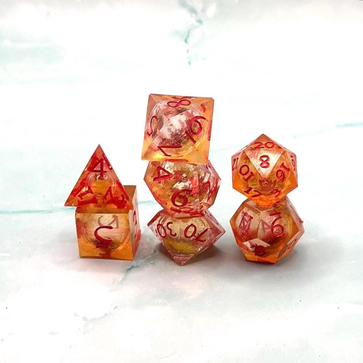 Orange Fall Foliage Liquid Core Dice Set – sharp edge polyhedral DnD dice featuring swirling autumn leaves and shimmering orange liquid core. Perfect for tabletop RPGs, Dungeons & Dragons, or dice collectors. Handmade resin dice with crisp numbers, glowing fall colors, and mesmerizing motion that captures the beauty of autumn. Ideal DnD gift or gaming accessory for players who love seasonal fantasy aesthetics.