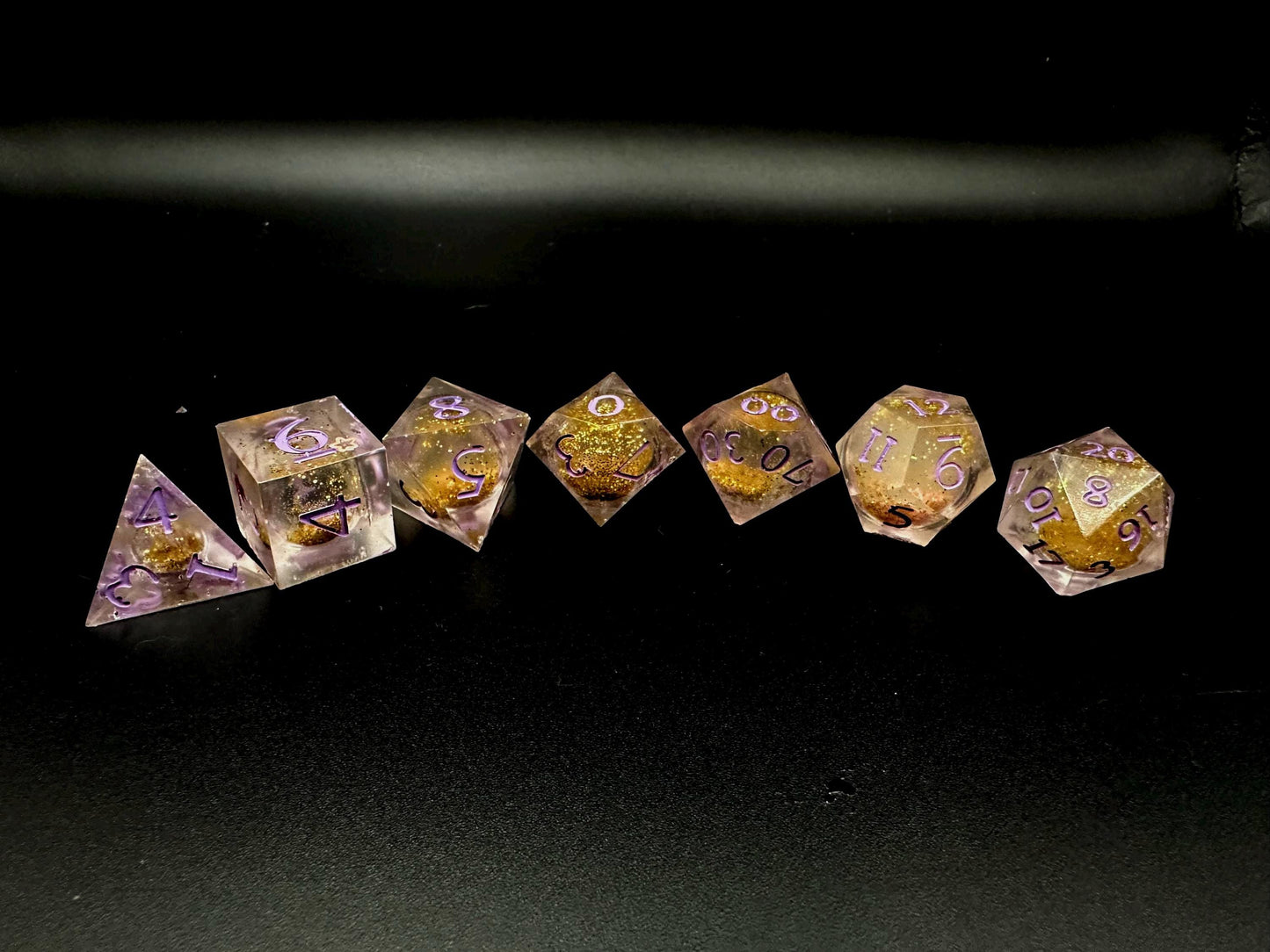 Light purple, pink, and gold glitter liquid core dice set shimmering with swirling metallic sparkle. Handcrafted polyhedral resin dice filled with floating glitter and vibrant liquid core for mesmerizing movement. Perfect for Dungeons & Dragons, tabletop RPGs, and dice collectors. Elegant pastel tones with gold accents add a magical, fantasy-inspired aesthetic for gaming sessions or gift giving.