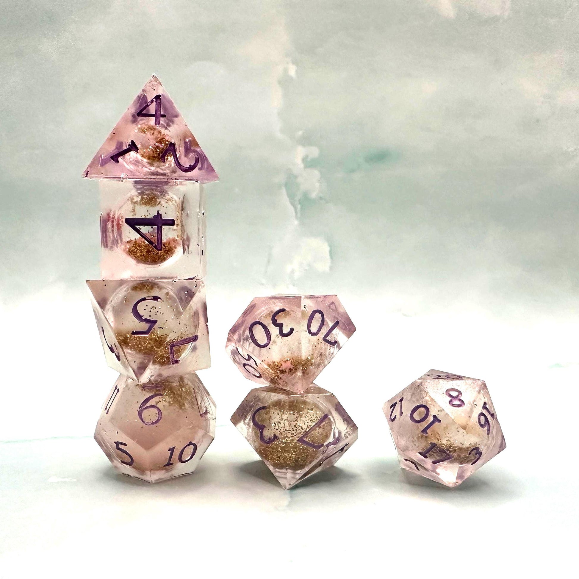 Light purple, pink, and gold glitter liquid core dice set shimmering with swirling metallic sparkle. Handcrafted polyhedral resin dice filled with floating glitter and vibrant liquid core for mesmerizing movement. Perfect for Dungeons & Dragons, tabletop RPGs, and dice collectors. Elegant pastel tones with gold accents add a magical, fantasy-inspired aesthetic for gaming sessions or gift giving.