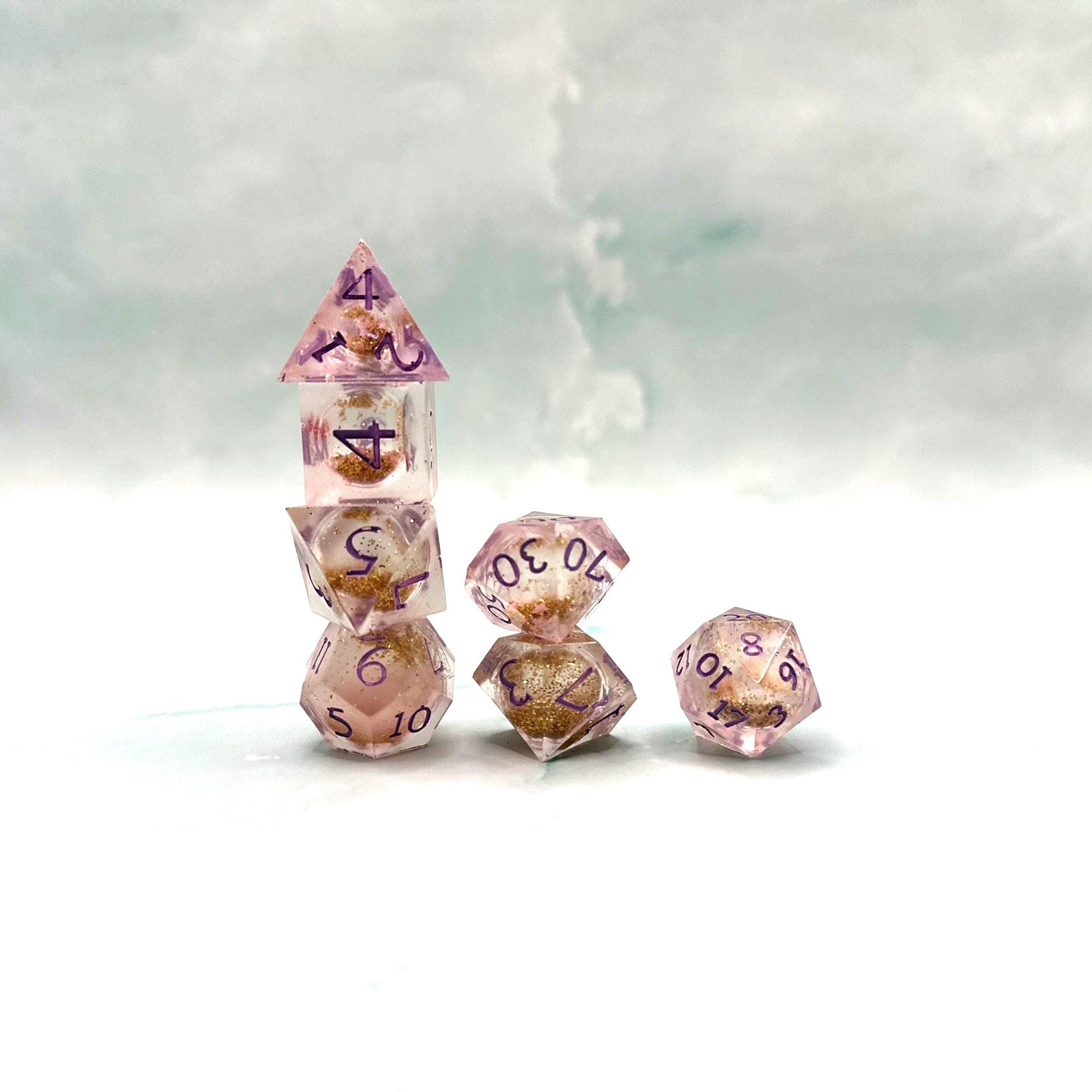 Light purple, pink, and gold glitter liquid core dice set shimmering with swirling metallic sparkle. Handcrafted polyhedral resin dice filled with floating glitter and vibrant liquid core for mesmerizing movement. Perfect for Dungeons & Dragons, tabletop RPGs, and dice collectors. Elegant pastel tones with gold accents add a magical, fantasy-inspired aesthetic for gaming sessions or gift giving.