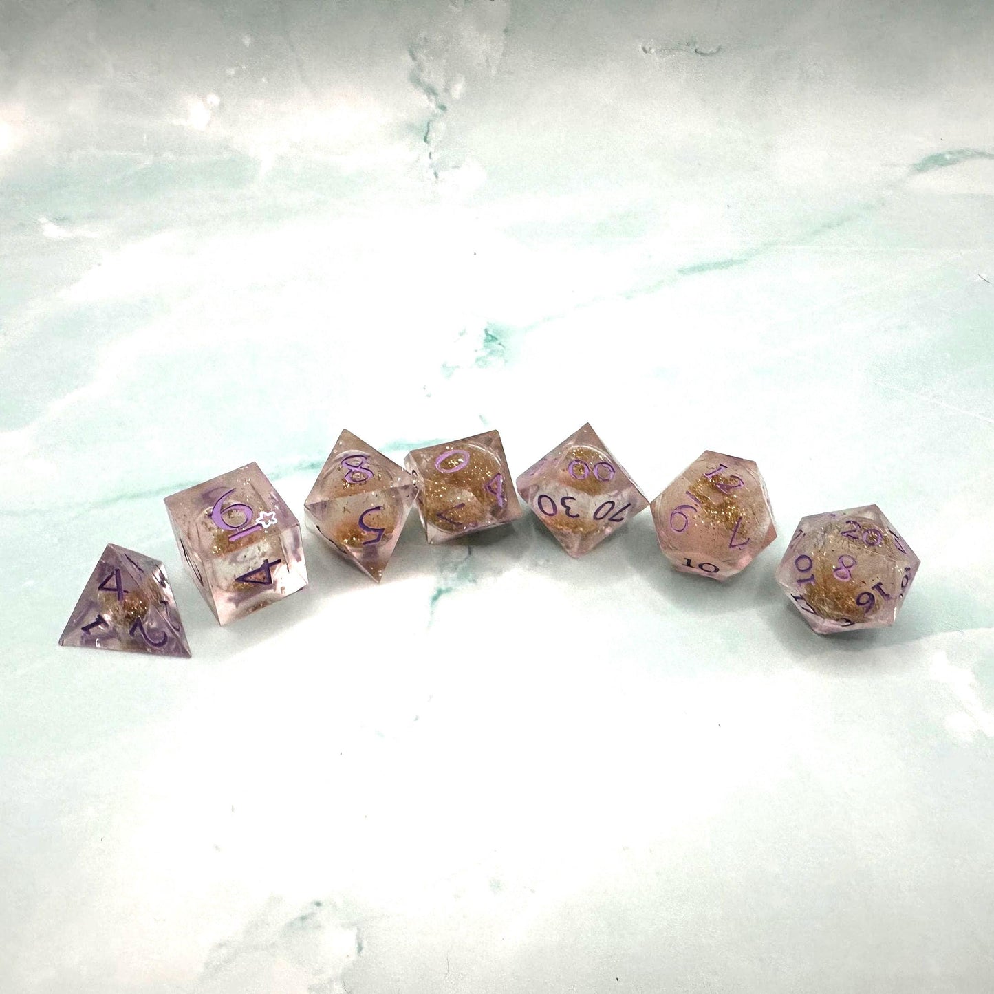Light purple, pink, and gold glitter liquid core dice set shimmering with swirling metallic sparkle. Handcrafted polyhedral resin dice filled with floating glitter and vibrant liquid core for mesmerizing movement. Perfect for Dungeons & Dragons, tabletop RPGs, and dice collectors. Elegant pastel tones with gold accents add a magical, fantasy-inspired aesthetic for gaming sessions or gift giving.
