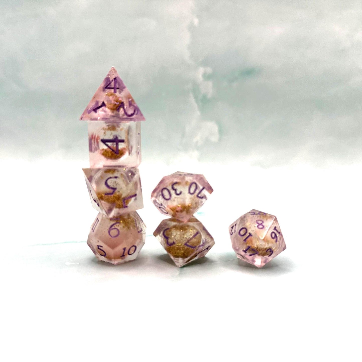 Light purple, pink, and gold glitter liquid core dice set shimmering with swirling metallic sparkle. Handcrafted polyhedral resin dice filled with floating glitter and vibrant liquid core for mesmerizing movement. Perfect for Dungeons & Dragons, tabletop RPGs, and dice collectors. Elegant pastel tones with gold accents add a magical, fantasy-inspired aesthetic for gaming sessions or gift giving.
