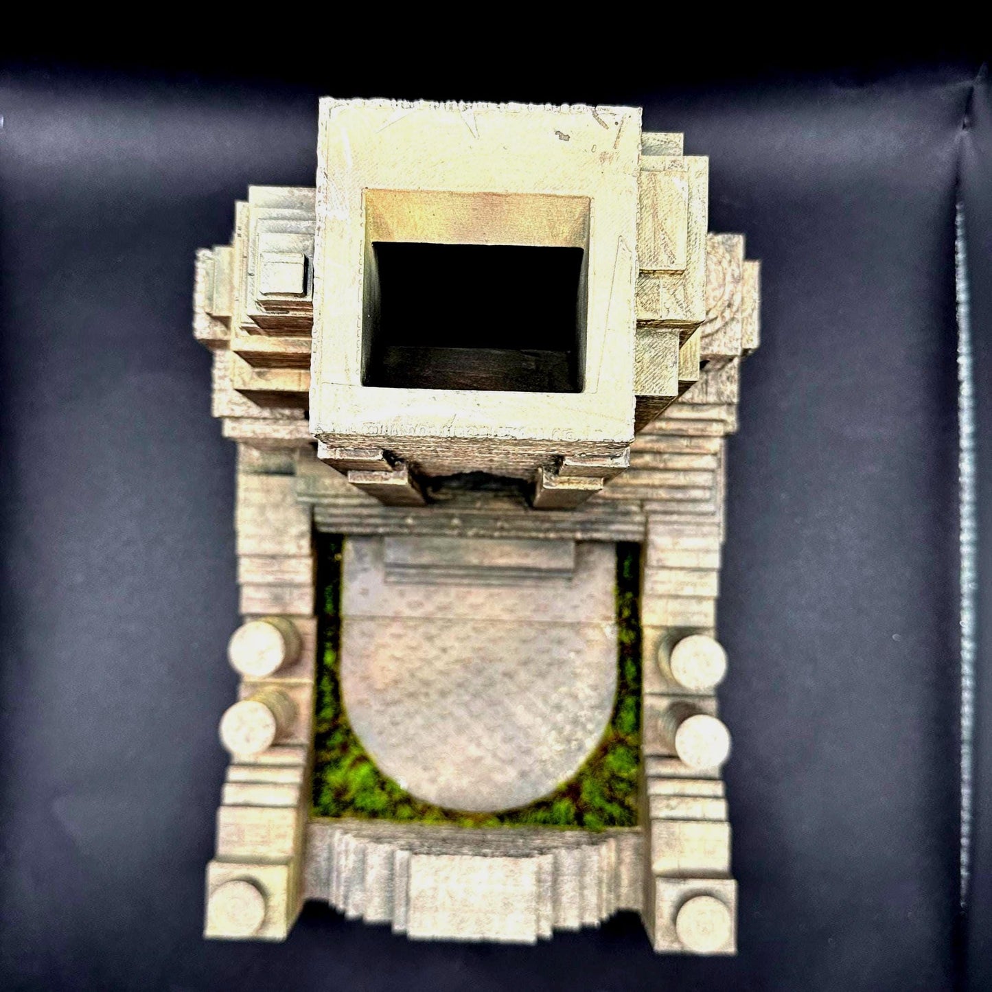 A handpainted explorer temple dice tower with a tan and brown color scheme. The tower features a detailed, textured design of a delapidated temple Laura Croft might explore. The tower has miniature green grass around the tray that catches the dice. Perfect for dice goblins and ttrpg lovers alike. The perfect item for your next dungeons and dragons campaign.