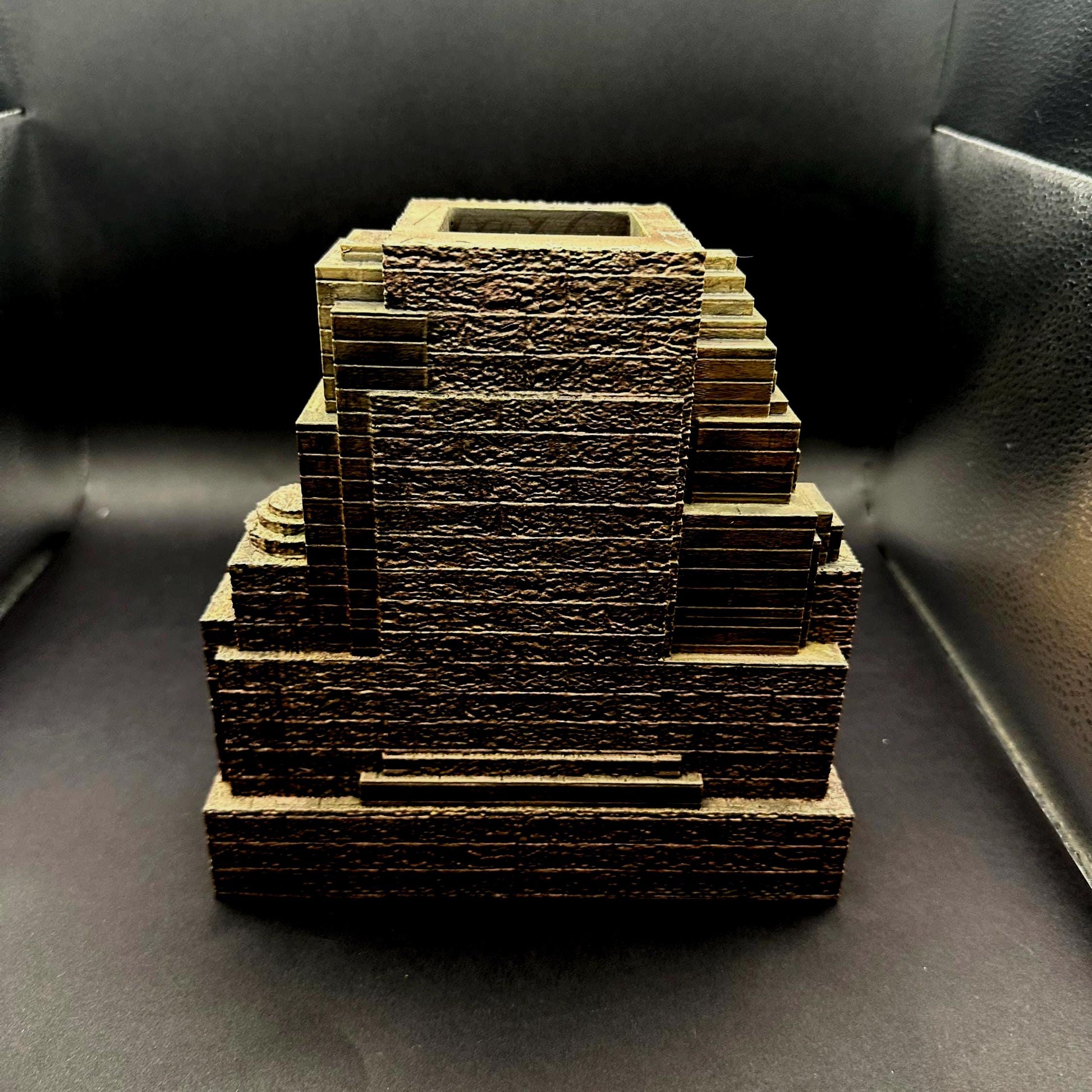 A handpainted explorer temple dice tower with a tan and brown color scheme. The tower features a detailed, textured design of a delapidated temple Laura Croft might explore. The tower has miniature green grass around the tray that catches the dice. Perfect for dice goblins and ttrpg lovers alike. The perfect item for your next dungeons and dragons campaign.