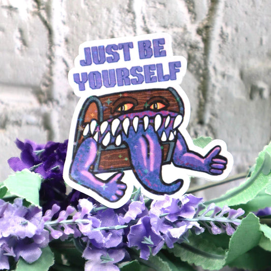 Holographic DnD mimic sticker with a grinning treasure chest and the phrase Just Be Yourself, perfect for laptops, water bottles, and tabletop RPG fans.