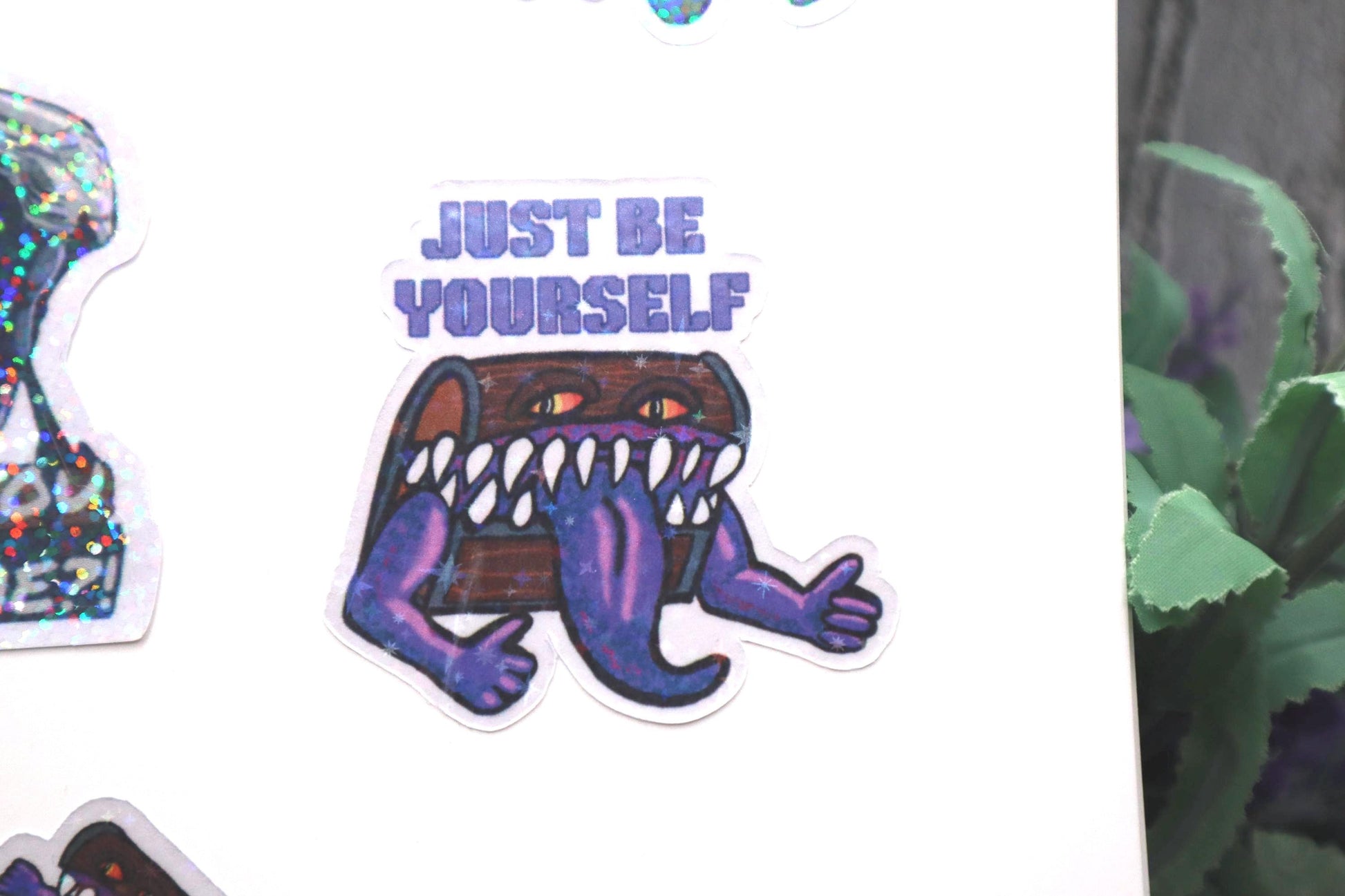 Holographic DnD mimic sticker with a grinning treasure chest and the phrase Just Be Yourself, perfect for laptops, water bottles, and tabletop RPG fans.