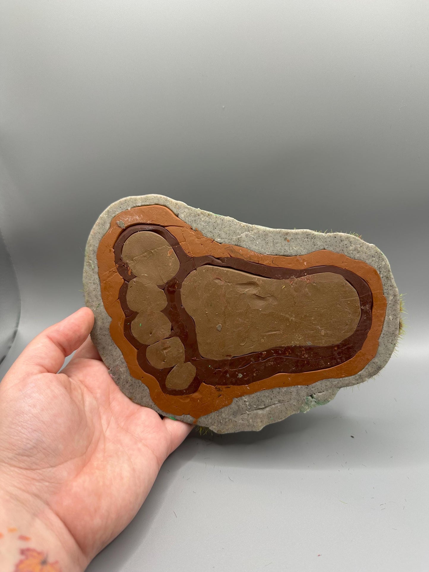 Cute handmade polymer clay dice tray and holder for a cryptid lover with a baby Bigfoot theme. Perfect gift for RPG, D&D, cryptid lovers and fantasy lovers. Baby Bigfoot sitting at the edge of a full grown Bigfoot foot print in the woods surrounded by fake grass and clay mushrooms. No AI used in the making of this dice tray!