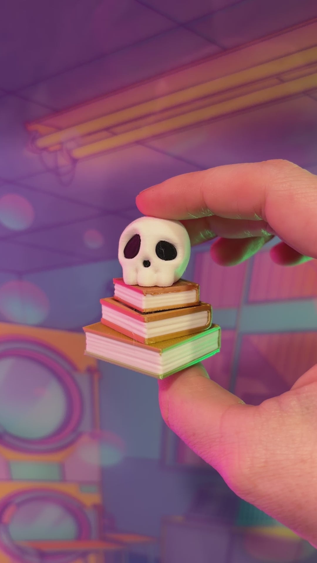 3D printed skull fidget clicker on an ombre stack of books.