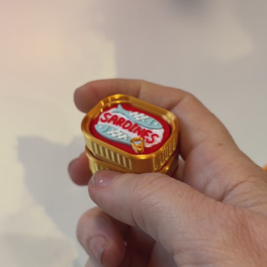 Sardine tin fidget clicker inspired by tinned fish packaging.