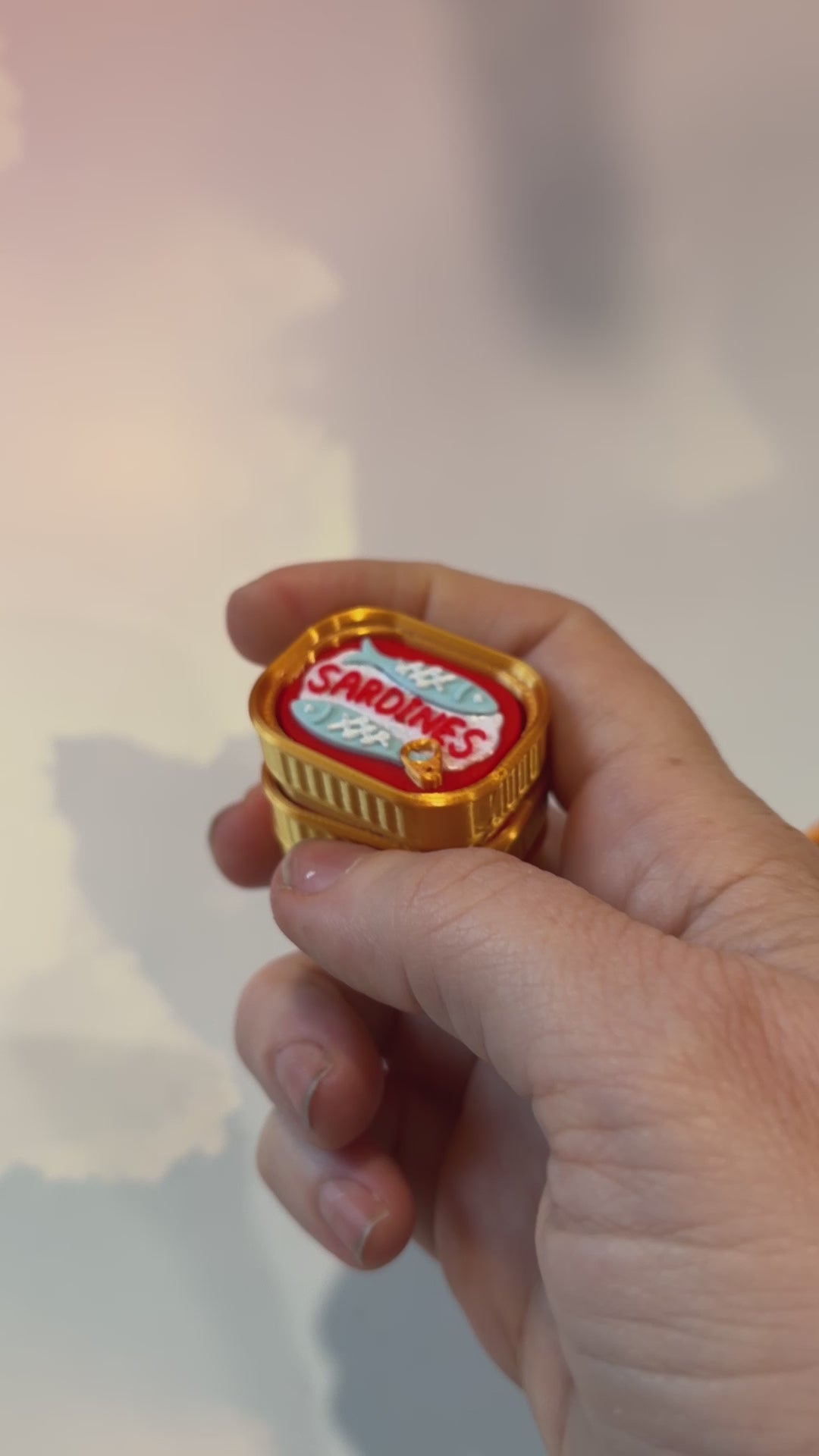 Sardine tin fidget clicker inspired by tinned fish packaging.