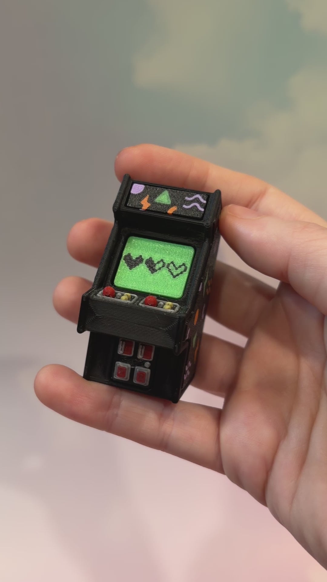 Mini retro arcade machine fidget clicker keychain with colorful 90s-inspired graphics, green screen, and 3D printed design, available in clicky or silent.
