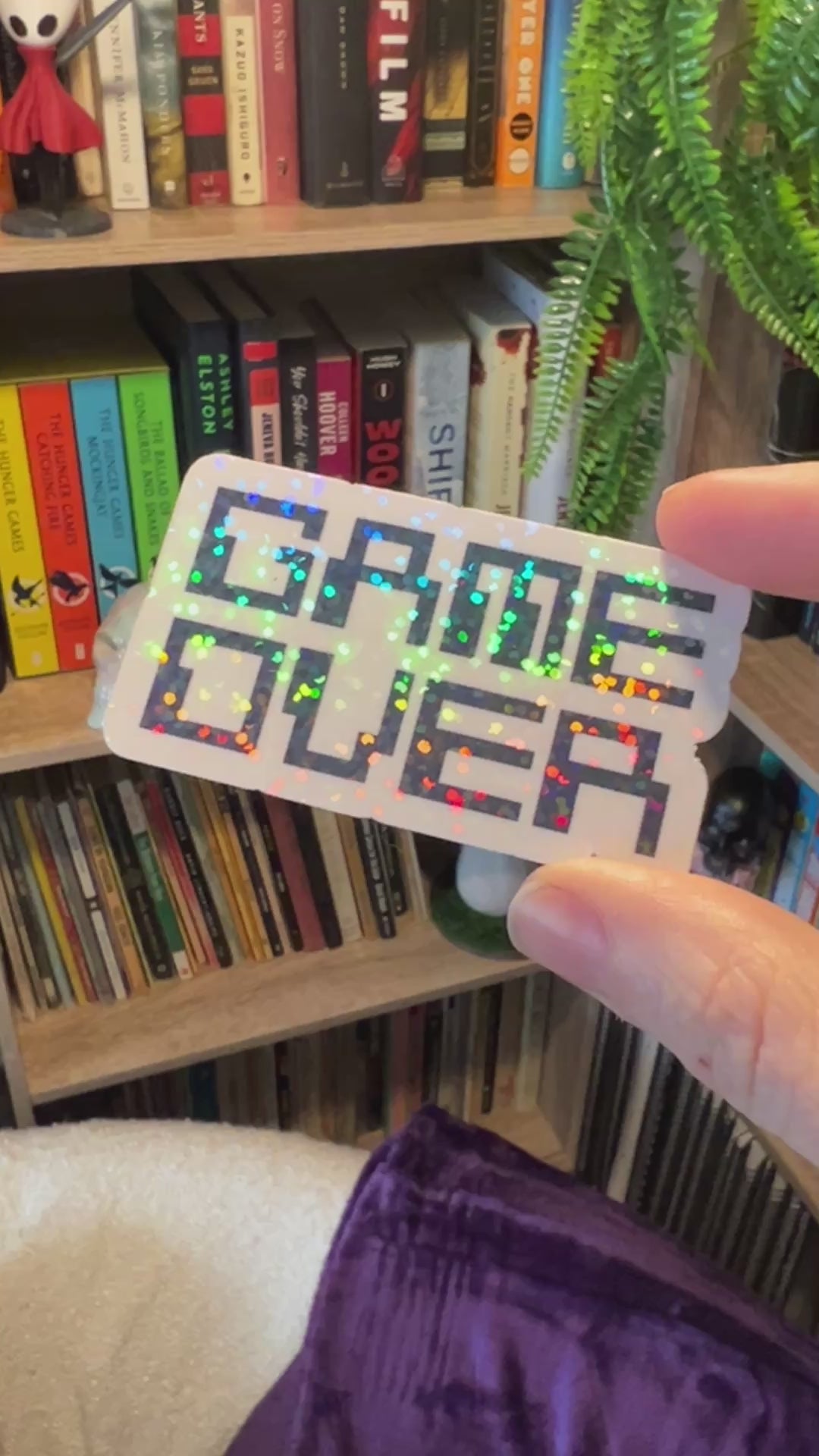 Holographic black and white gamer sticker that says GAME OVER in pixelated retro font. Water-resistant vinyl decal for laptops, bottles, consoles.