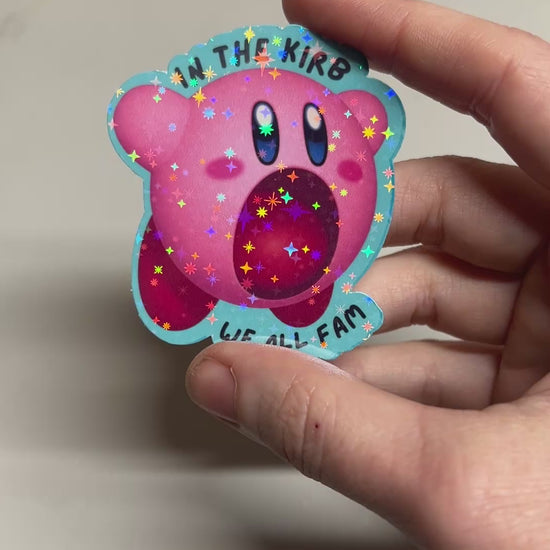 Holographic vinyl sticker featuring a cute Kirby with the phrase "In the Kirb, We All Fam." Perfect for laptops, water bottles, or gamer gear.