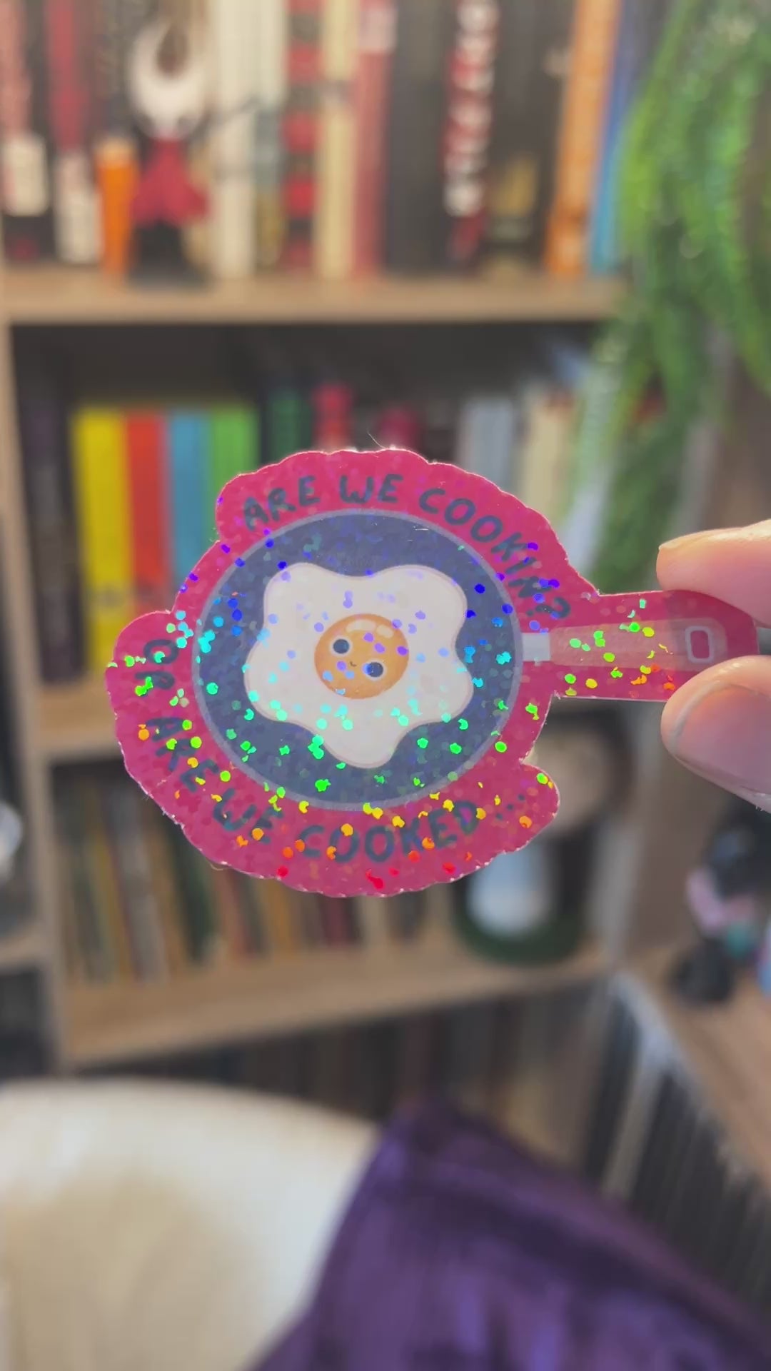 Holographic vinyl sticker with a wide-eyed egg in a frying pan and the phrase “Are We Cooking or Are We Cooked?” Funny kitchen-themed design.