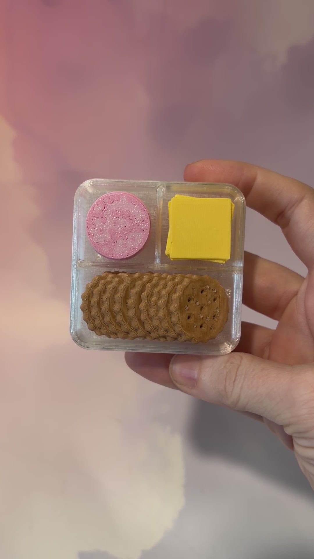 3D printed mini snack box fidget clicker with ham, cheese, and crackers under a semi-transparent lid. Ham and cheese have soft silent presses, while the crackers make satisfying audible clicks.