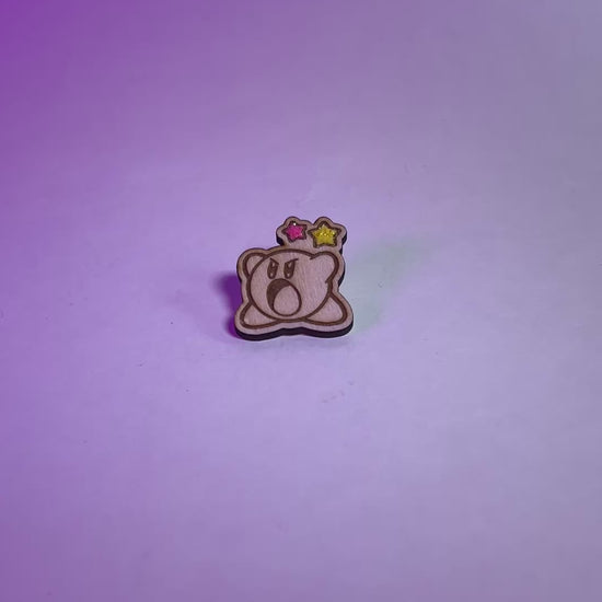 Cute Kirby wood pin with laser engraving and glittery star accents. Handmade gamer brooch for Nintendo fans, perfect for jackets or bags.