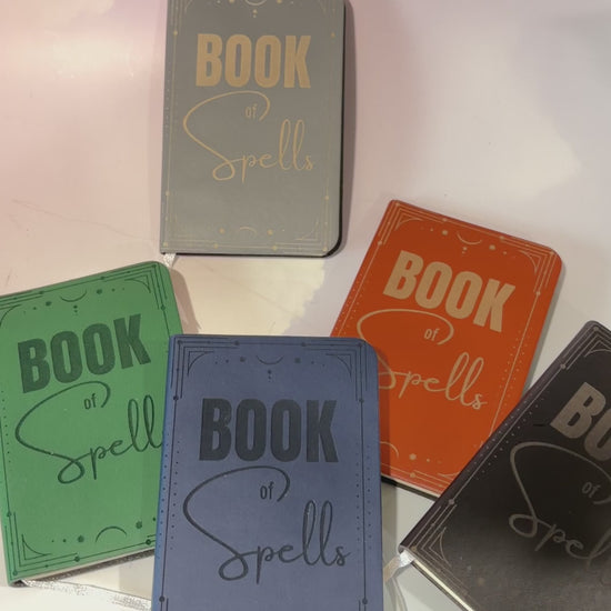 Mini green leather notebook with “Book of Spells” laser engraved on the cover in black lettering. Approximately 4 x 2.5 inches, with 50 lined pages. Available in brown, green, blue, gray, and black.

