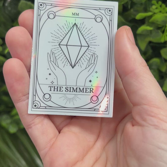 Silver Holographic Sims tarot card sticker featuring "The Simmer" with a radiant plumbob design. A must-have for Sims fans, gamers, and lovers of geeky decor.