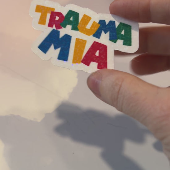 Holographic Trauma Mia sticker in retro video game style lettering.