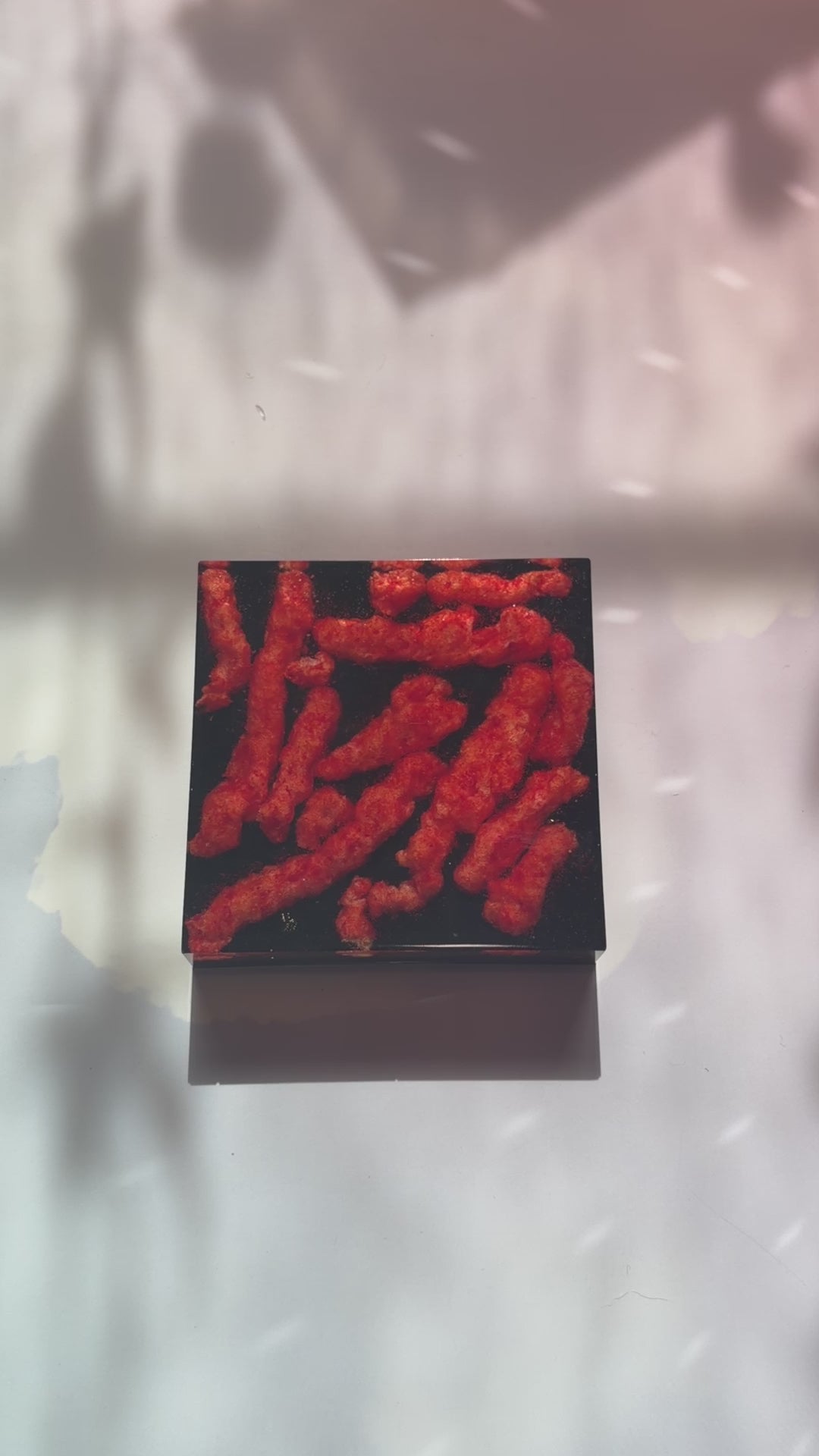 Resin coaster inlaid with Hot Cheetos and black backing.