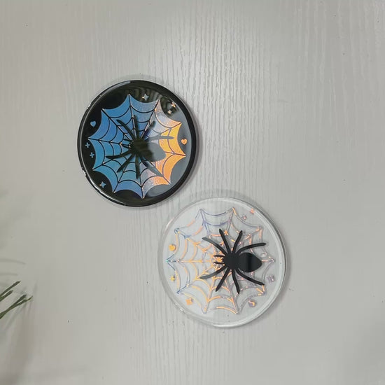 Pastel goth spiderweb coasters featuring a handmade resin design with intricate spiderwebs. Perfect for adding a dark, spooky aesthetic to any home. These unique coasters blend pastel colors with a goth twist, great for goth or Halloween-themed decor