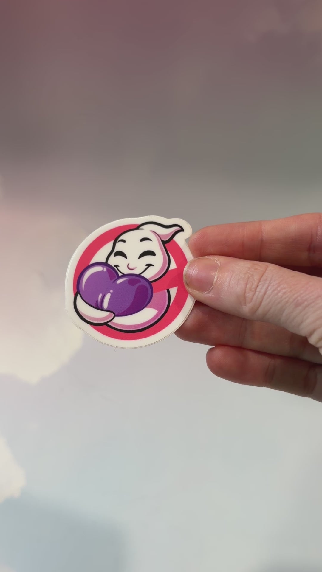 A vinyl sticker featuring a playful ghost hugging a purple heart, inspired by Ghostbusters. Perfect for laptops, water bottles, and notebooks.