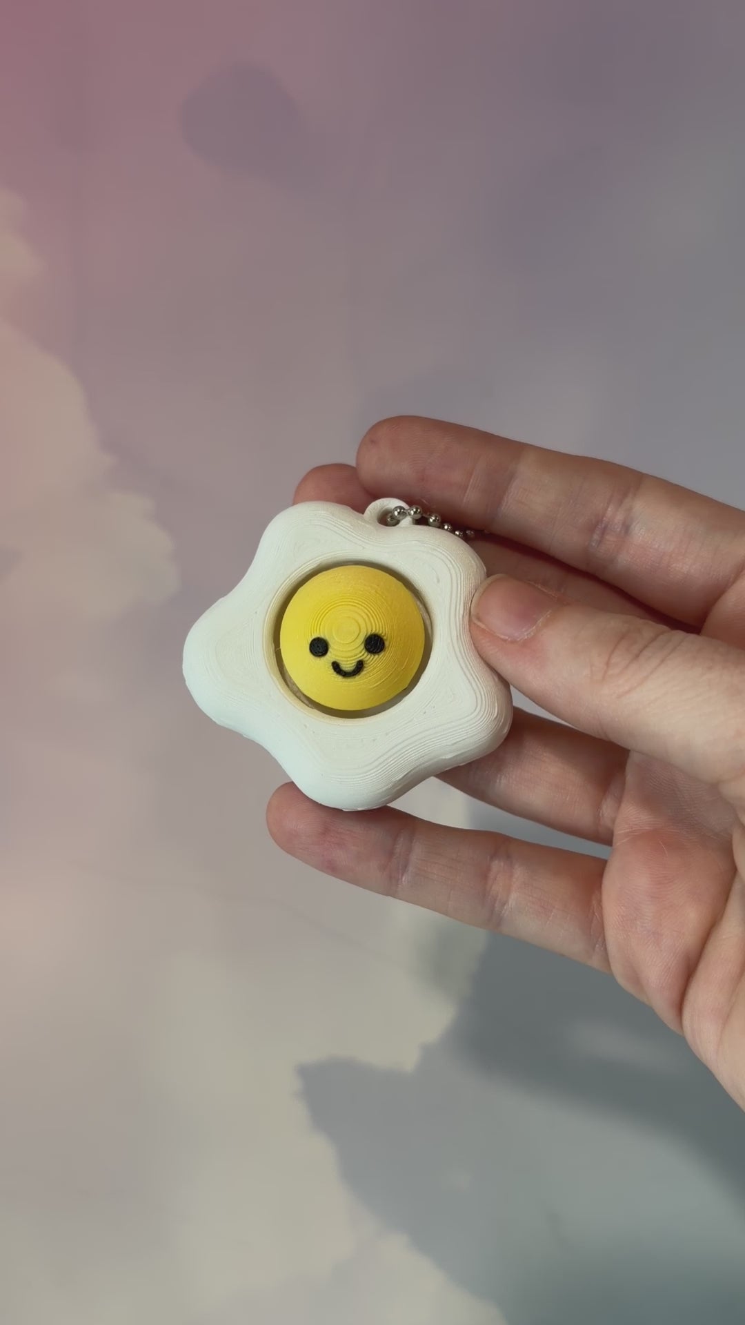 Fried egg shaped fidget clicker toy with a white egg and yellow yolk design, fun food themed desk accessory and satisfying fidget gift.
