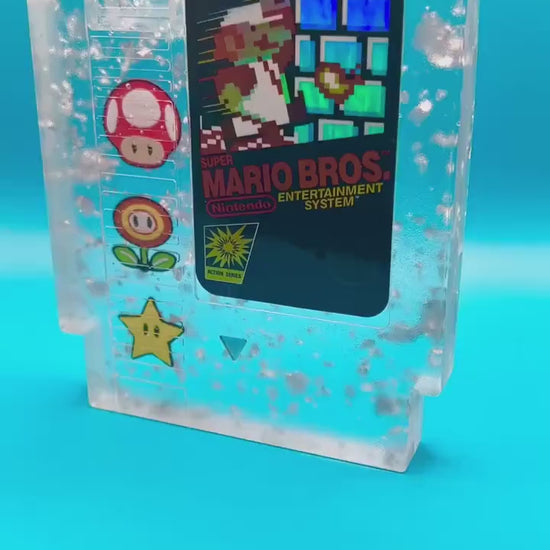 Handmade resin art featuring a retro Super Mario Bros NES cartridge with classic icons like the mushroom, fire flower, and star. Perfect for gamers, collectors, or unique home decor to add a nostalgic touch to any space.