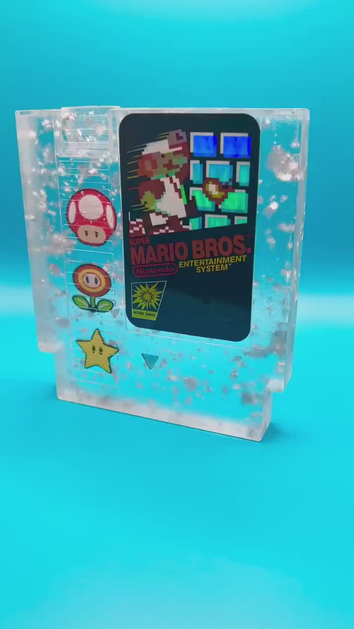 Handmade resin art featuring a retro Super Mario Bros NES cartridge with classic icons like the mushroom, fire flower, and star. Perfect for gamers, collectors, or unique home decor to add a nostalgic touch to any space.