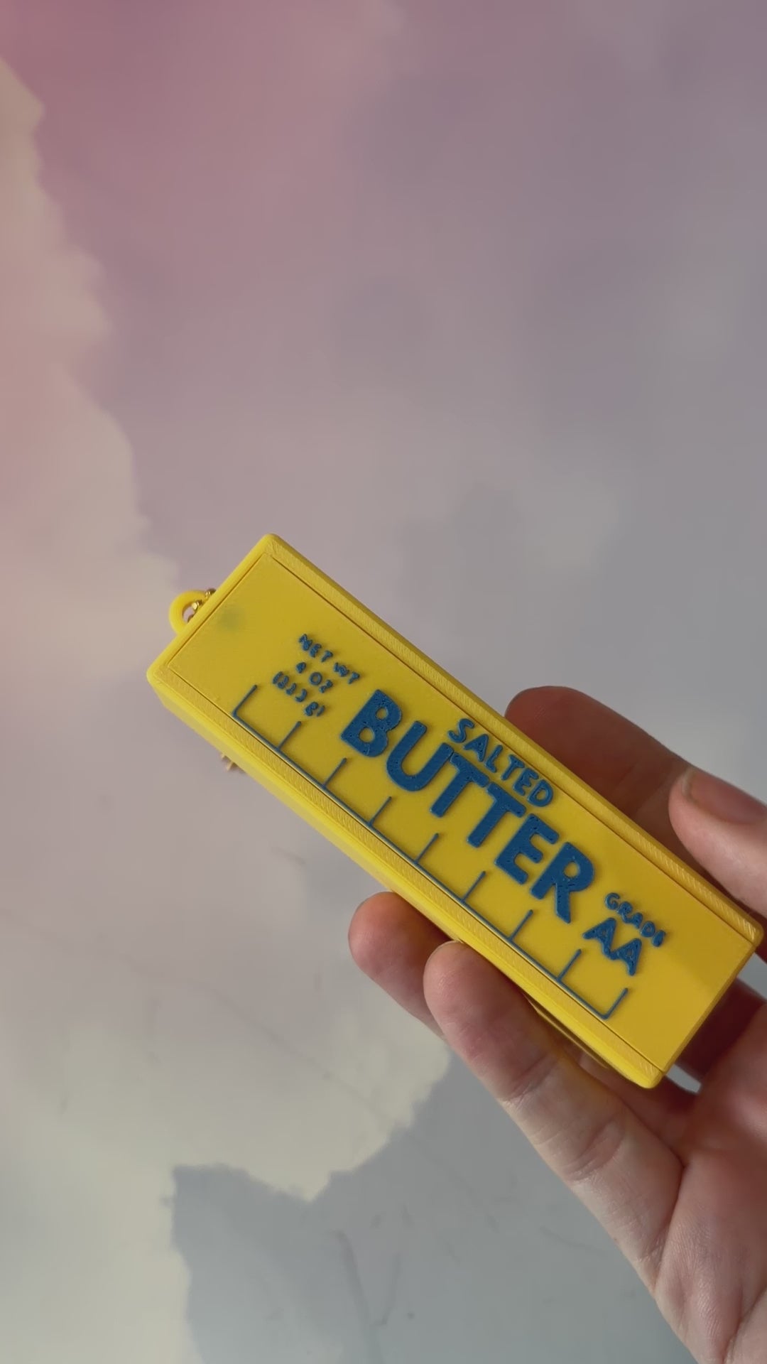 3D printed stick of butter bag charm with gold hardware, classic TBSP markings, Grade AA label, and net weight details. Sliding top hides a lipstick or chapstick in a magnetic compartment.