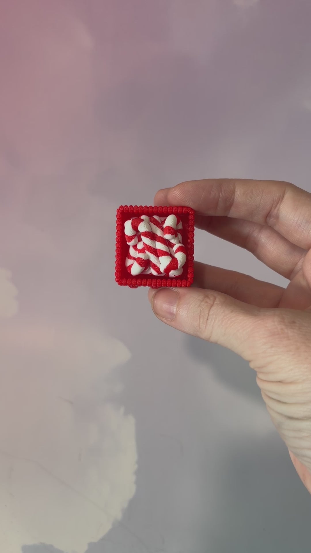 3D printed Christmas fidget clicker featuring a red basket filled with red-and-white candy canes. Available with a clicky or silent mechanism. A festive holiday sensory toy and stocking stuffer for Christmas lovers.