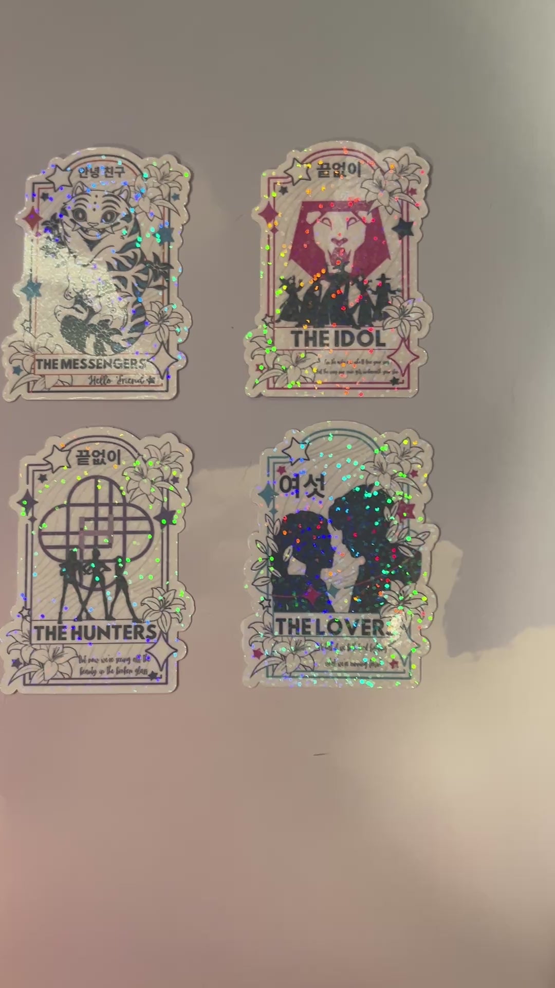 Holographic vinyl tarot sticker set featuring KPOP demon hunter characters: Lovers, Idol, Hunters, and Messengers. Vibrant, 3-inch water-resistant decals. Featuring Huntrix, The Saja Boys, Derpy Tiger, and Rumi and Jinu.