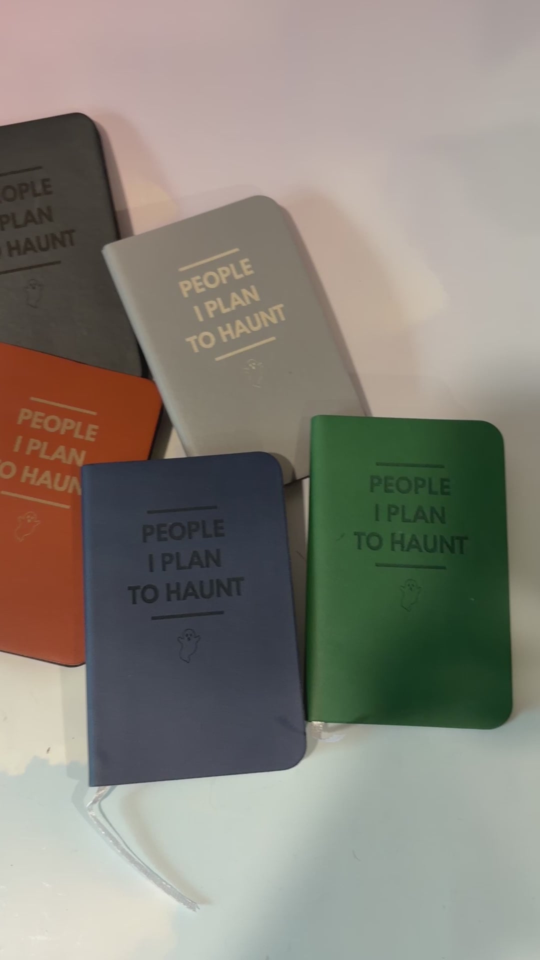 Mini blue notebook with “People I Plan to Haunt” laser engraved in black lettering and a tiny ghost illustration. Approximately 4 x 2.5 inches, with 50 lined pages. Available in brown, green, blue, gray, and black.
