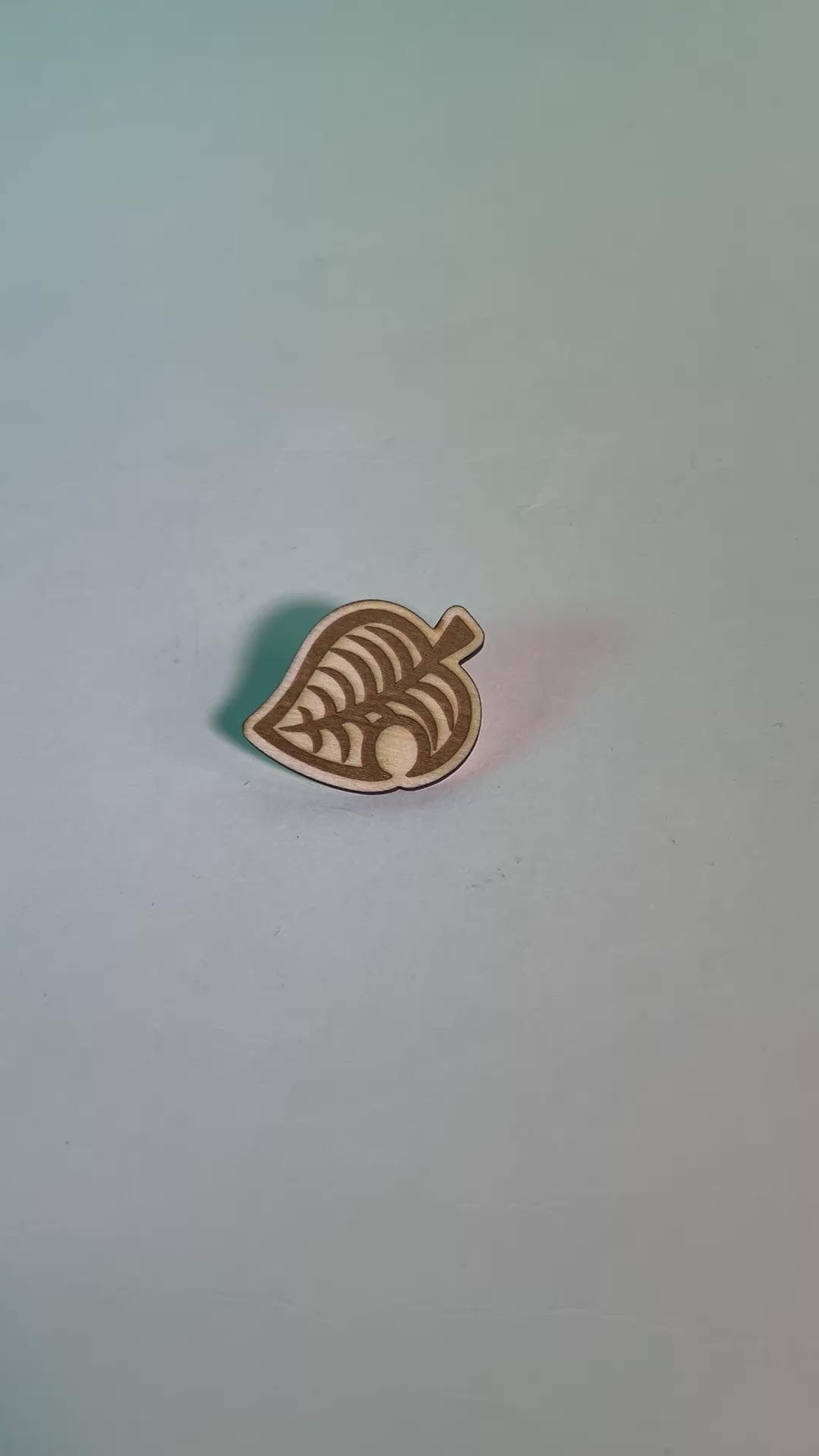 Laser engraved wood pin shaped like the Animal Crossing leaf, perfect gamer gift or accessory for backpacks, jackets, or collectors of gaming-themed items.