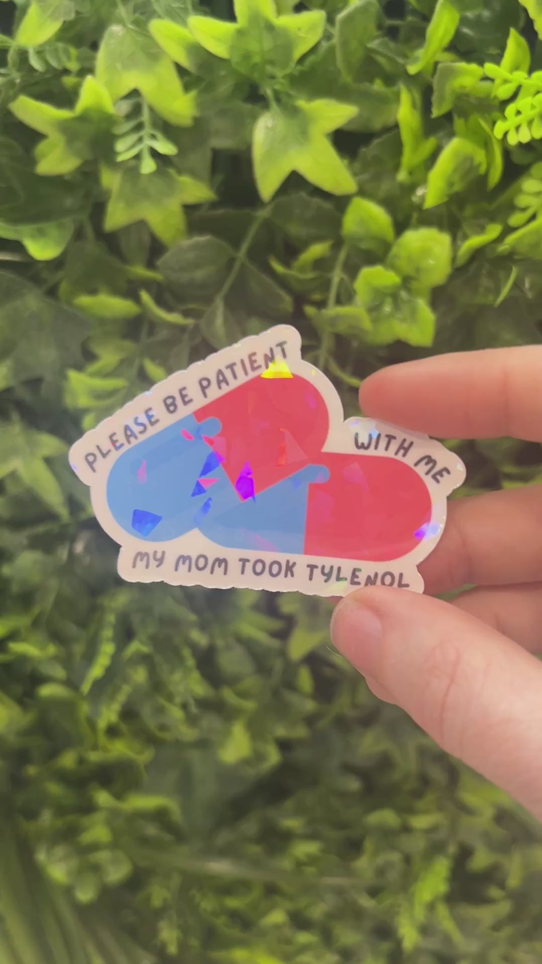 Holographic sticker featuring two pills and the phrase “Please be patient with me my mom took Tylenol.” Funny, shiny mental health vinyl decal for laptops, water bottles, and more.